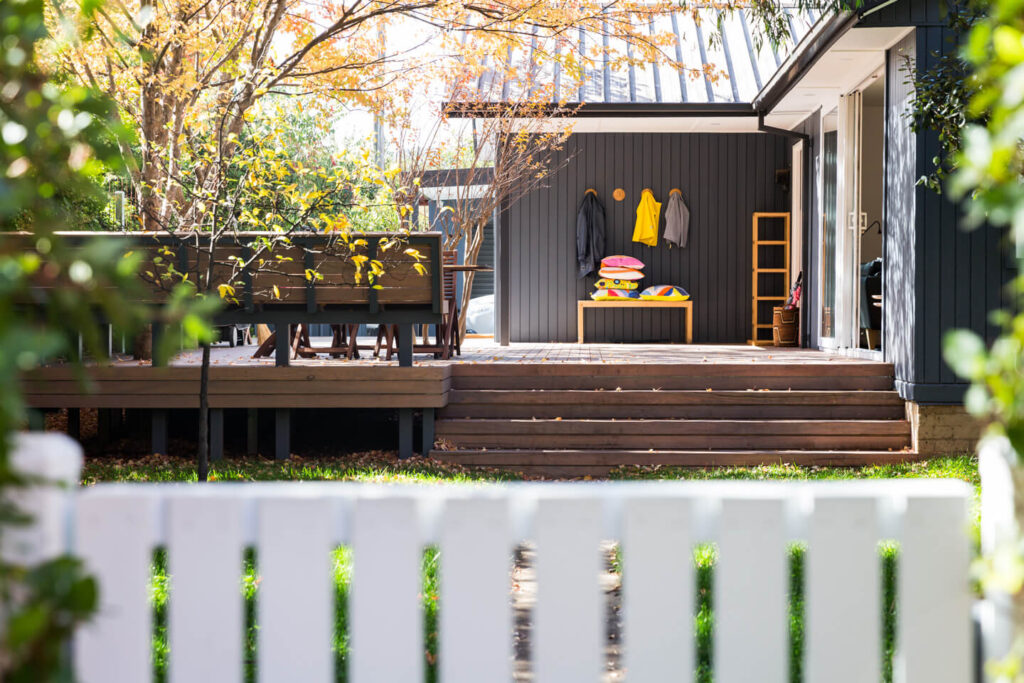 Front deck and facade of a Canberra house designed by Architecture Republic showing autumn colours. Fence in foreground.