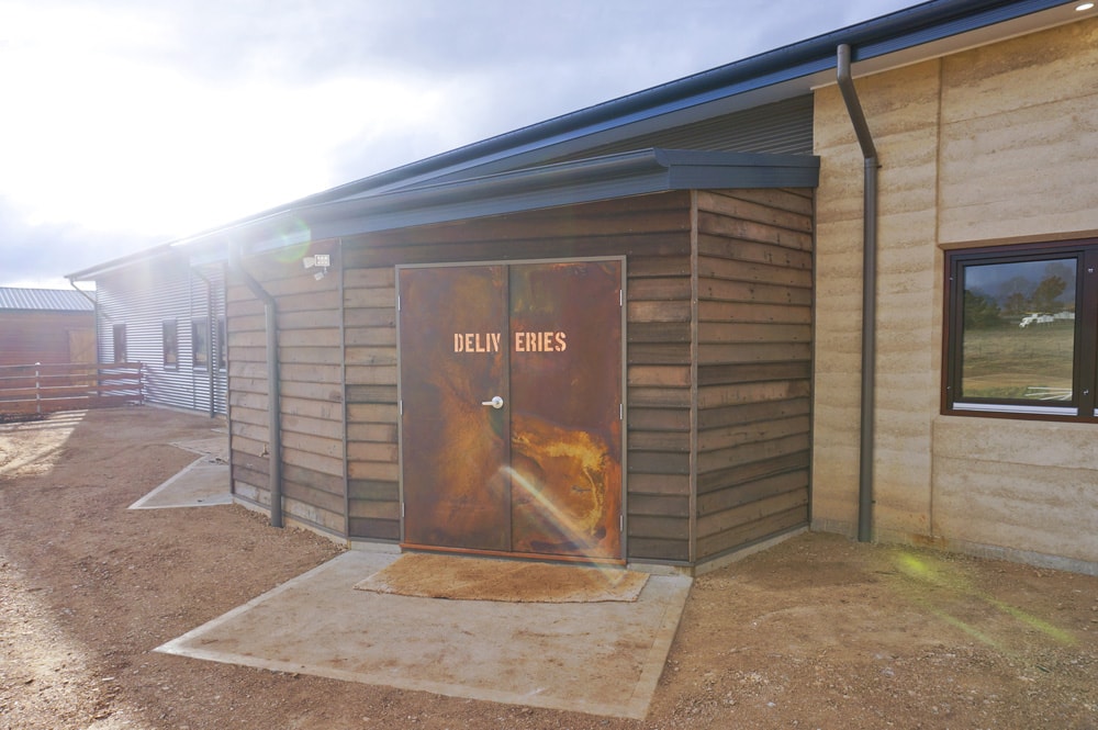 Rustic copper and coreten steel 'deliveries' door on a Rammed Earth building. Vet hospital by Architecture Republic, Bowral