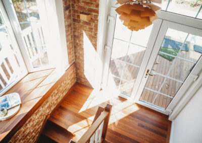 Timber staircase with window seat with feature brick walls. Pendant hangs, attractively, from ceiling.