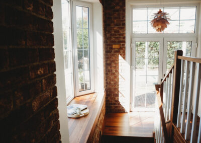Staircase with bay window and view out to garden beyond. Timber and brick with lots of natural light.