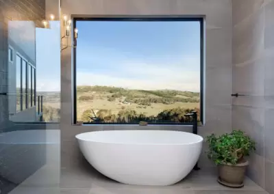 Architectural bath tub with a picture window above. View looking over regional Australian farmland