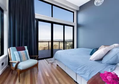 Inside master bedroom with blue wall and glass with rural views in the background.