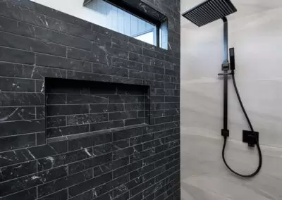 Shower space in en-suite. Black tapware and black feature tiles to one side.