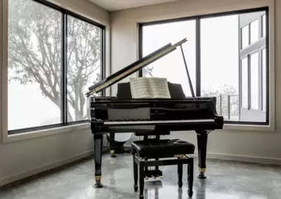 Grand piano overlooking foggy rural bush landscape out two corner windows.