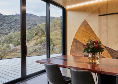Dinnig table in timber-clad room with bushland views beyond.