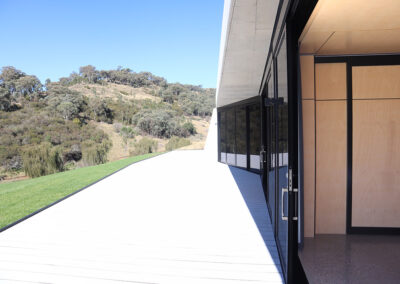 Entry room opening onto a gleaming white deck and the bush landscape beyond.