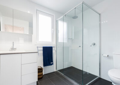 Renovated bathroom in Canberra. All white and chrome fixtures with a black tiled floor.