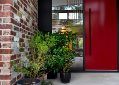 Entry porch with recycled brick walls and red front door.