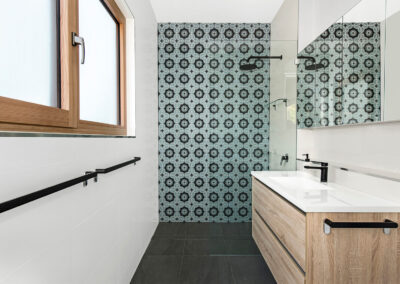 Small bathroom with green patterned feature tiles on the far wall.