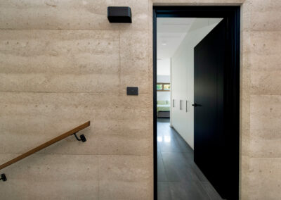 Entry to storage room with rammed earth wall and handrail in the foreground.